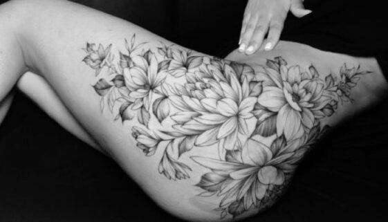 Tatuagem na coxa feminina floral em preto e cinza