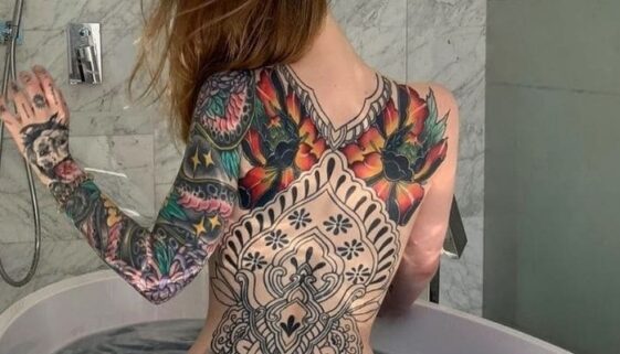 Tatuagem feminina nas costas peônias coloridas.