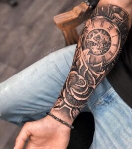 Tatuagem no braço masculino relógio em realismo com flor.
