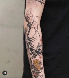 Tatuagem no braço masculino desenho abstrato com flores coloridas.