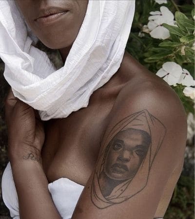Rosto de uma mulher negra tatuado no braço.