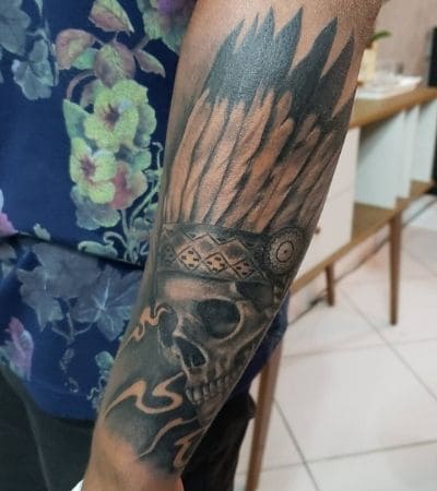 Caveira no braço com cocar de penas.