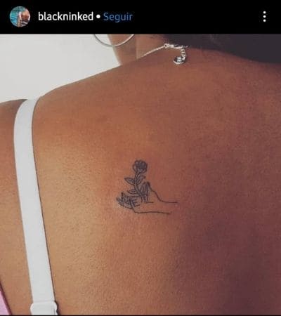 Tatuagem minimalista nas costas de uma mão com uma rosa.
