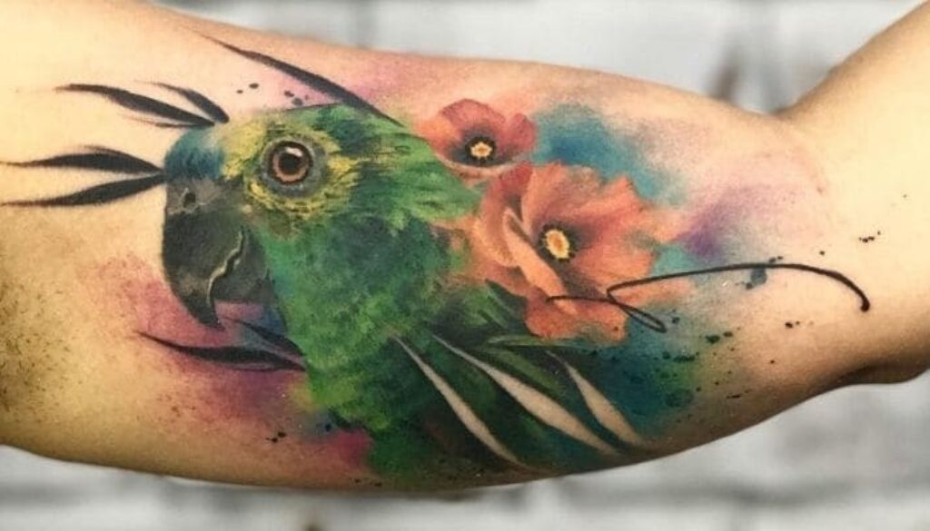 Tatuagem em aquarela, papagaio com flores num galho.
