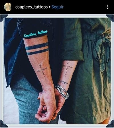 Tatuagem de casal com uma frase escrita em forma de cruz.
